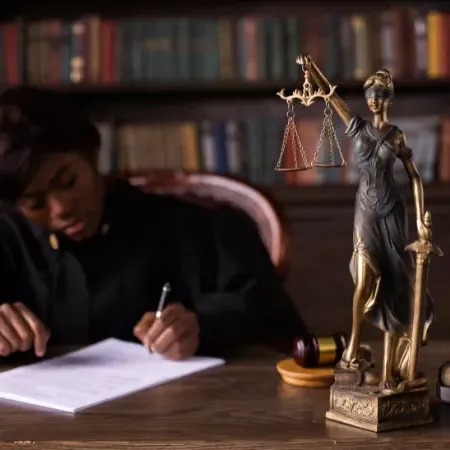 Statue of Justice on desk near woman writing